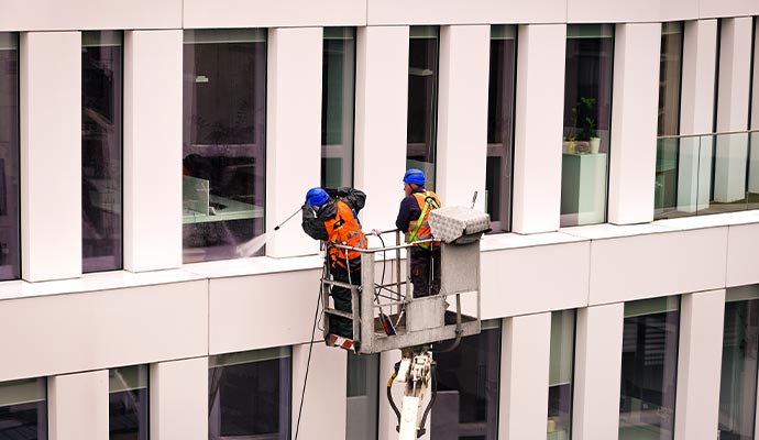 Person pressure washing commercial building