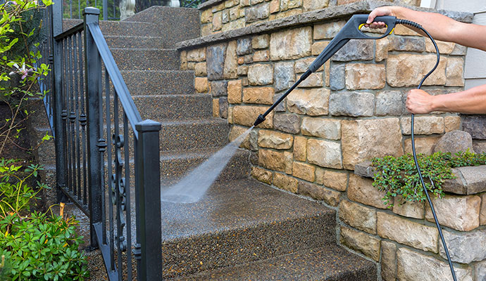 Worker pressure washing the window of a house