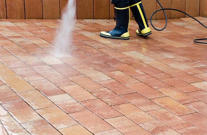 worker pressure washing in brick floor