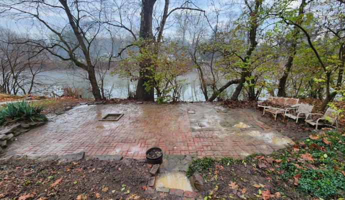 A brick patio overlooking a river with surrounding trees