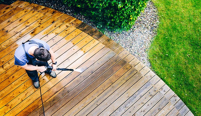 An expert cleaning residential outdoor deck with high-pressure washing