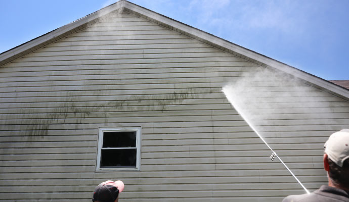 A person cleaning a house using pressure washer