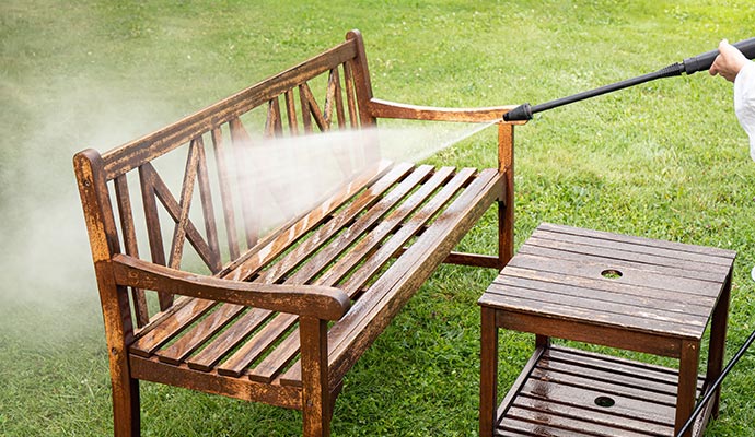 worker pressure washing outdoor furniture