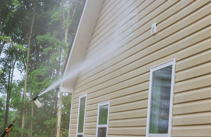 Worker soft-washing a house. 