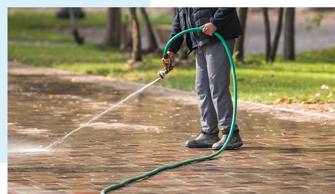 Worker cleaning sidewalk with pressure washing for a tidy and safe pedestrian path.